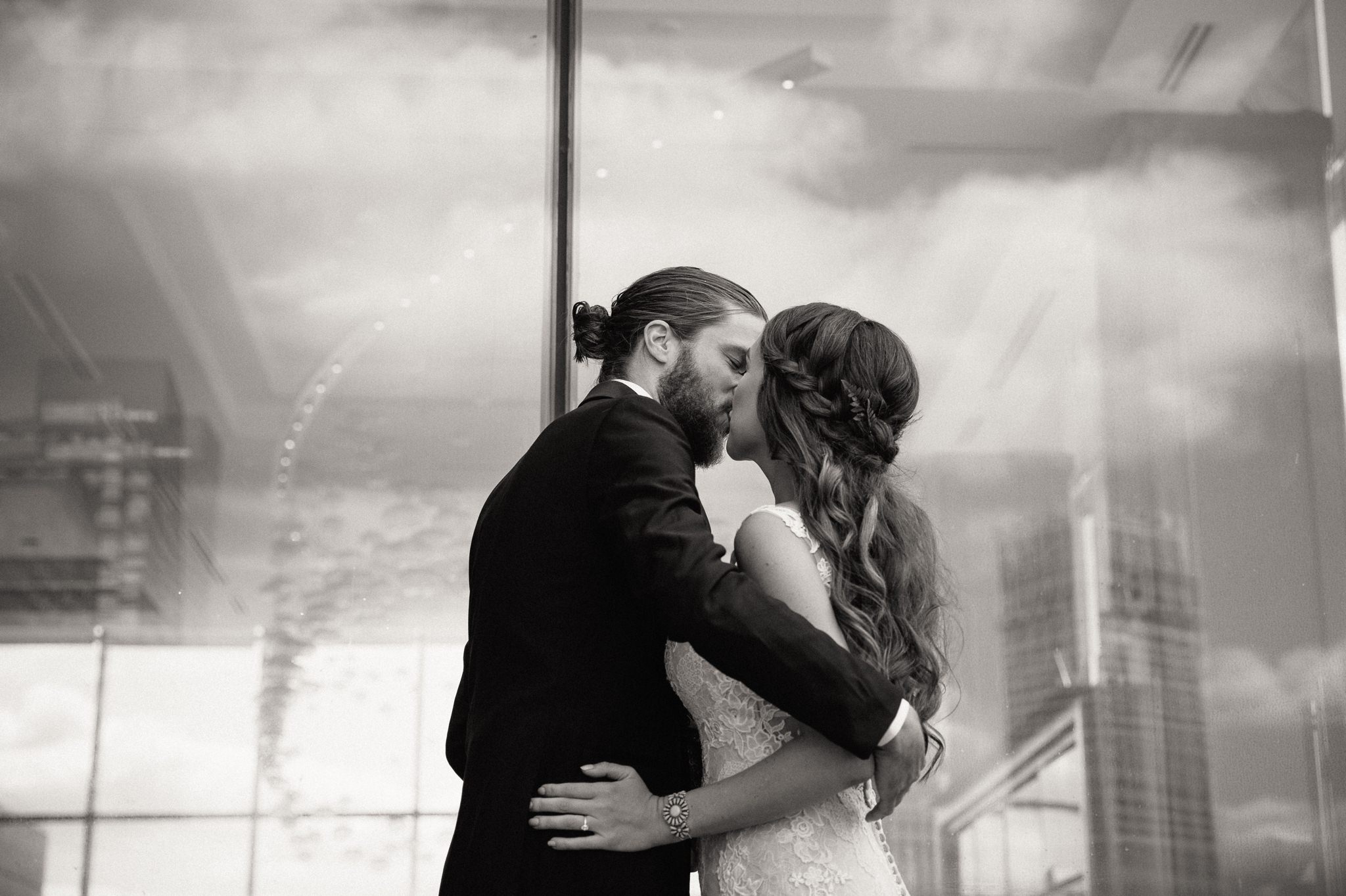 bride and groom kissing in front of glass window