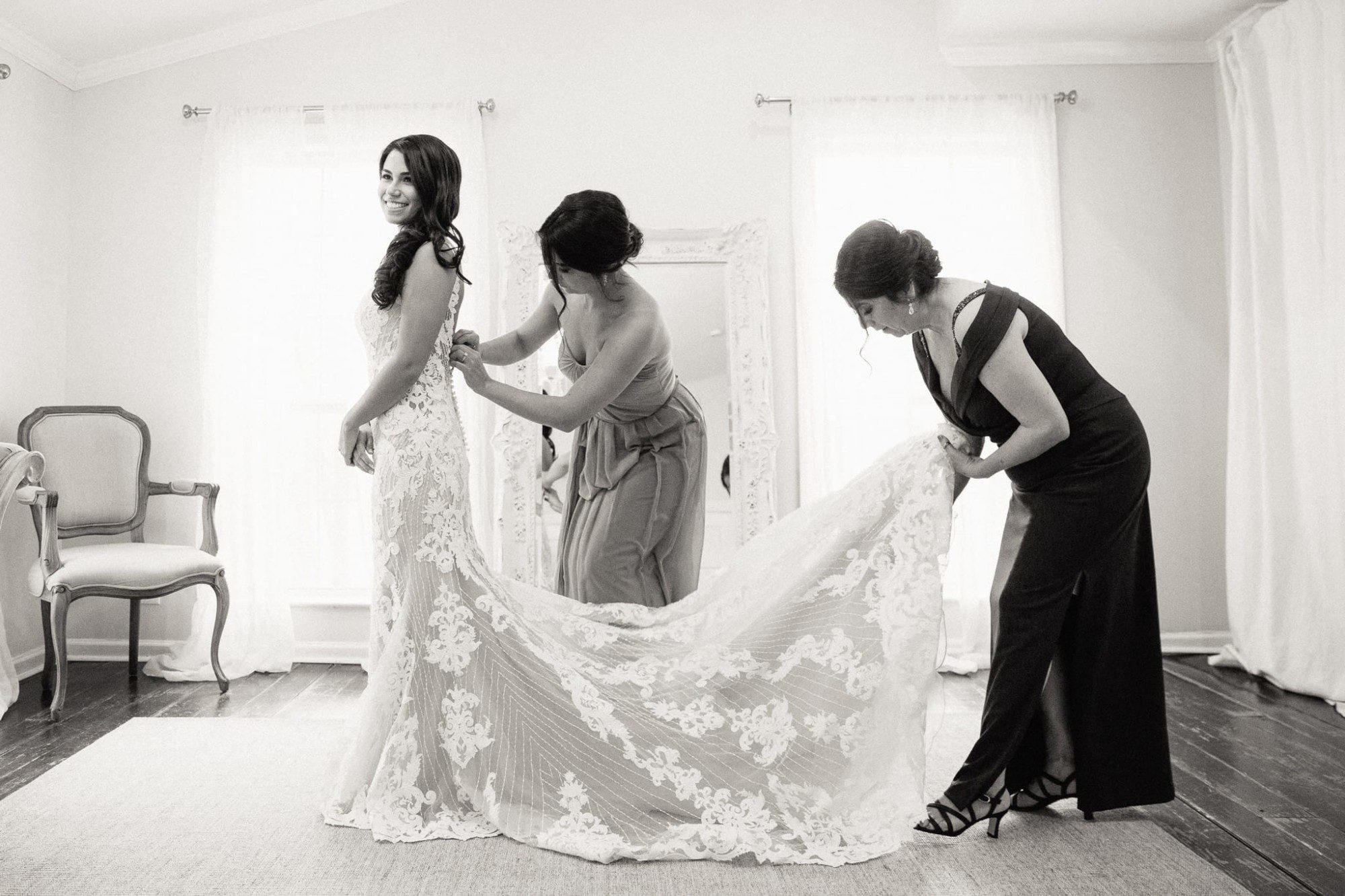 Bride's mother and sister helping her put on wedding dress