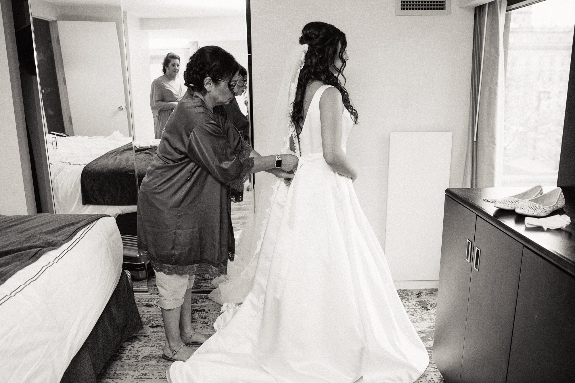 bride's mother helping bride with wedding dress