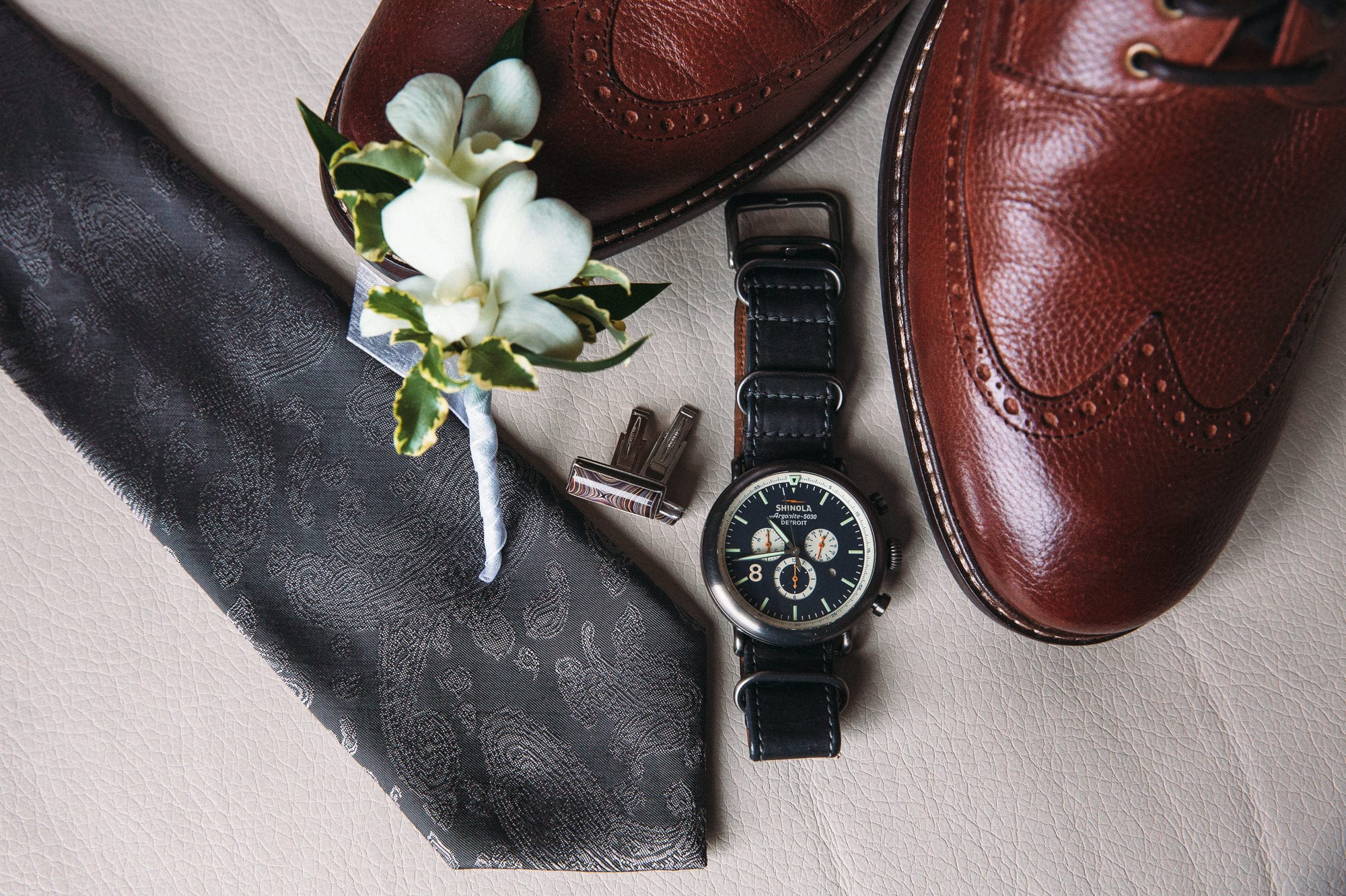 grooms shoes, tie, and Shinola watch displayed on sofa