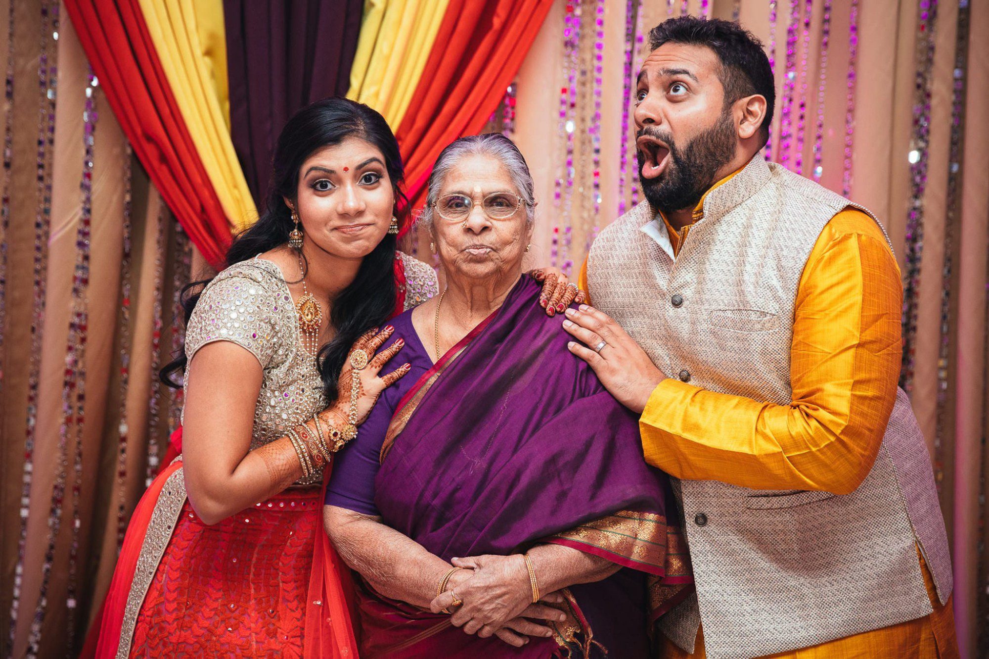 bride and groom making silly face with grandmother