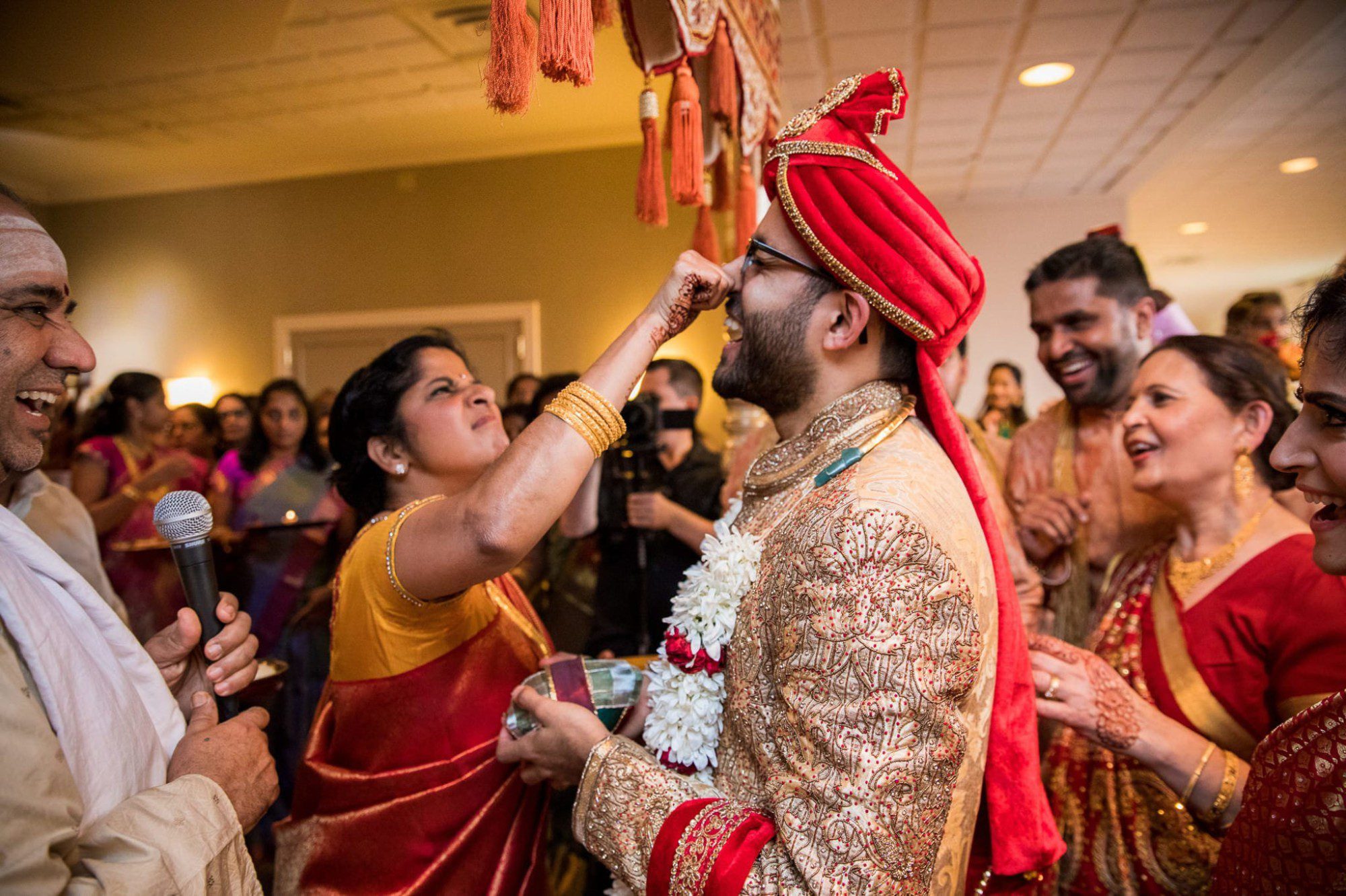 Indian wedding mother of bride pinching groom's nose