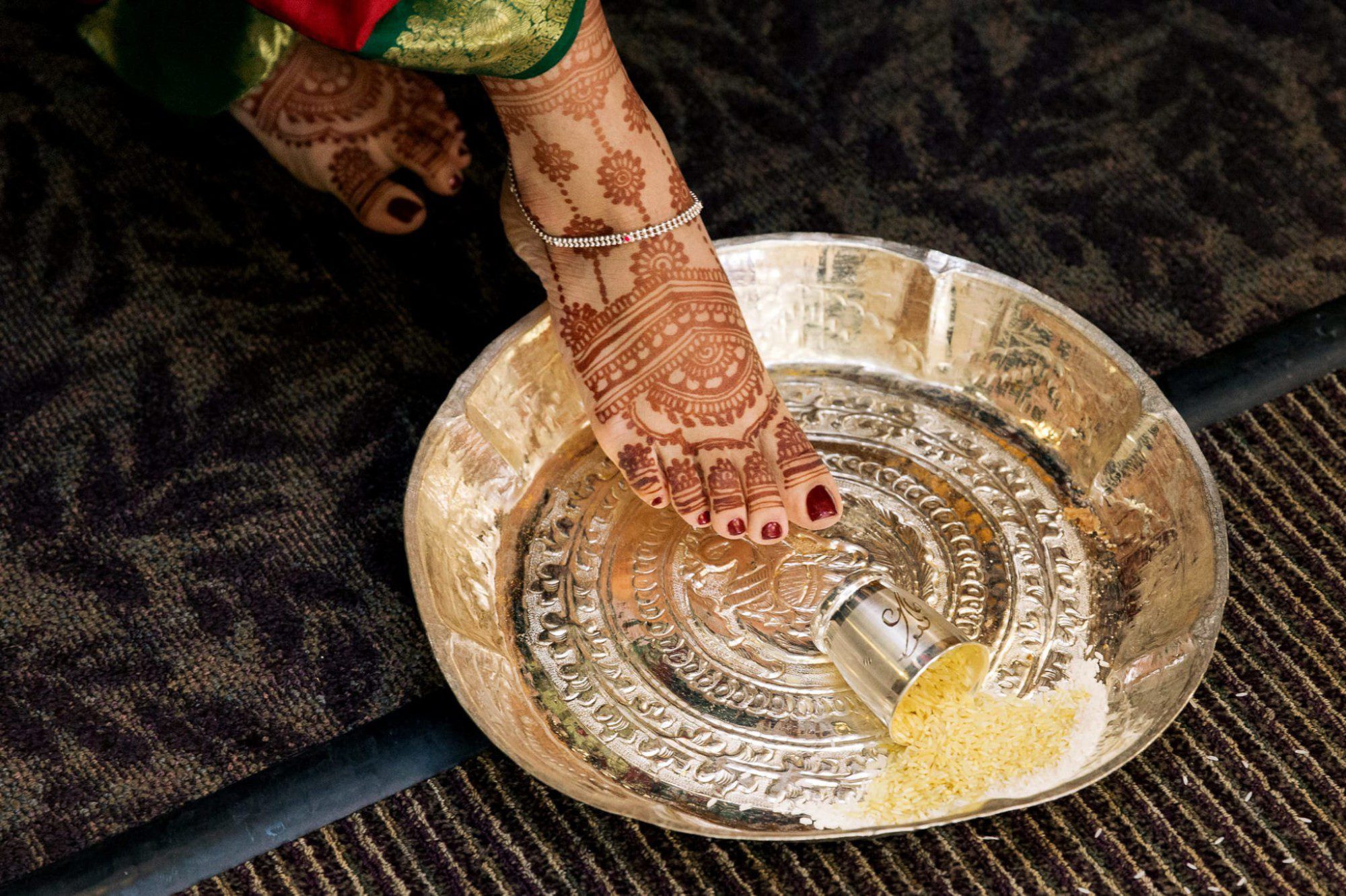 Indian ceremony tradition bride foot tipping over a cup of rice