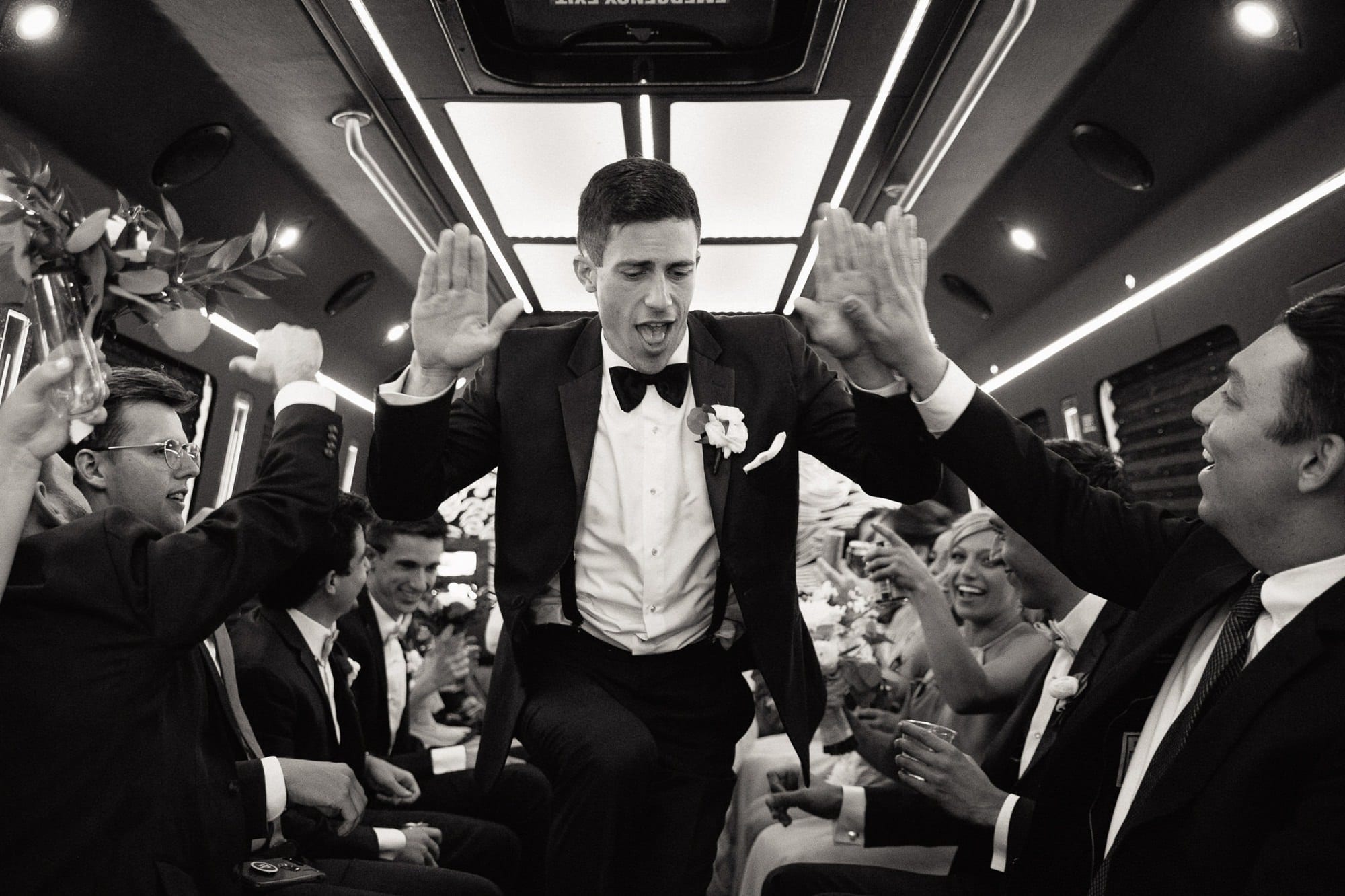 groom high-fiving wedding party on wedding bus