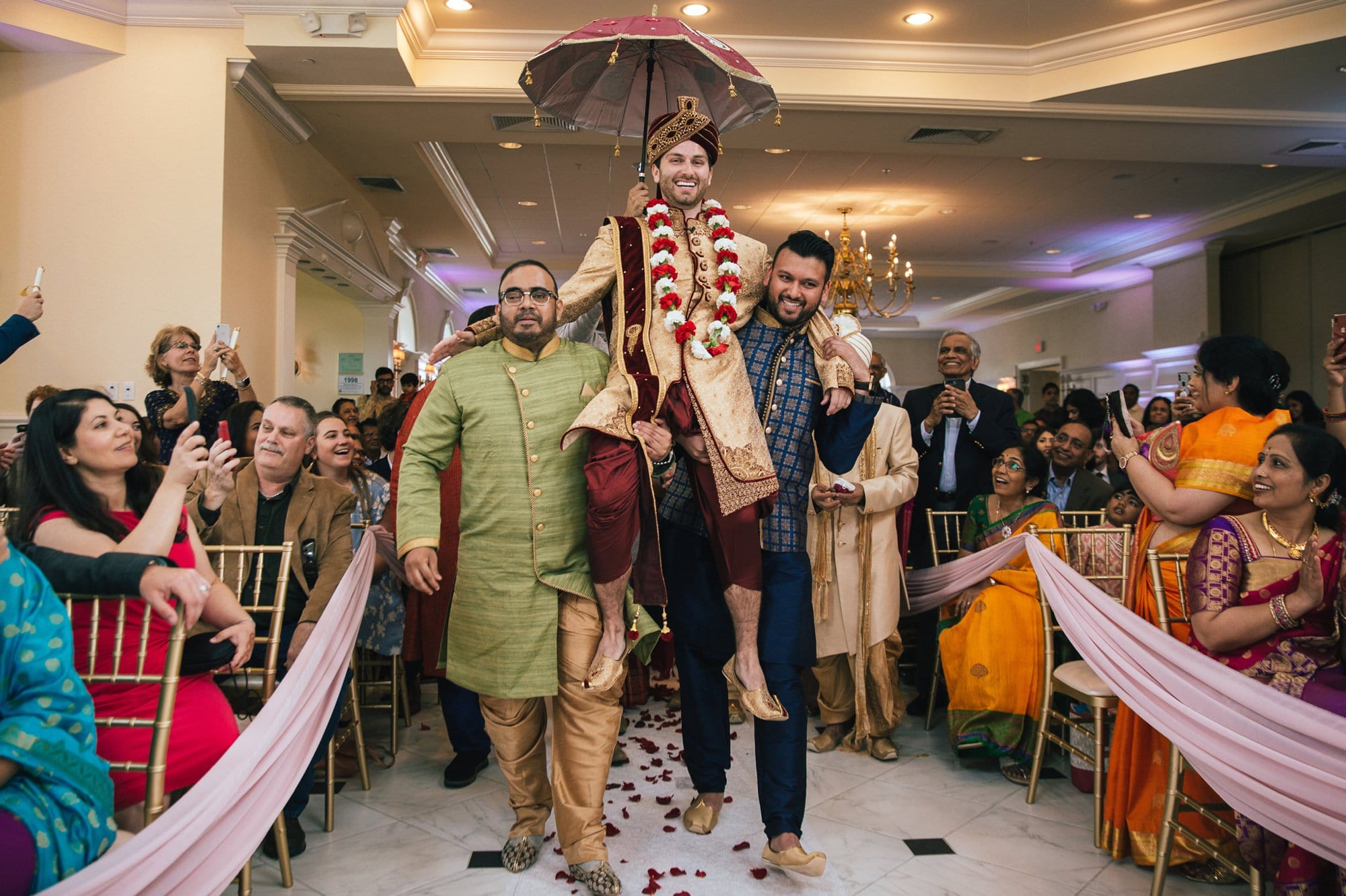 family members carrying groom down the aisle