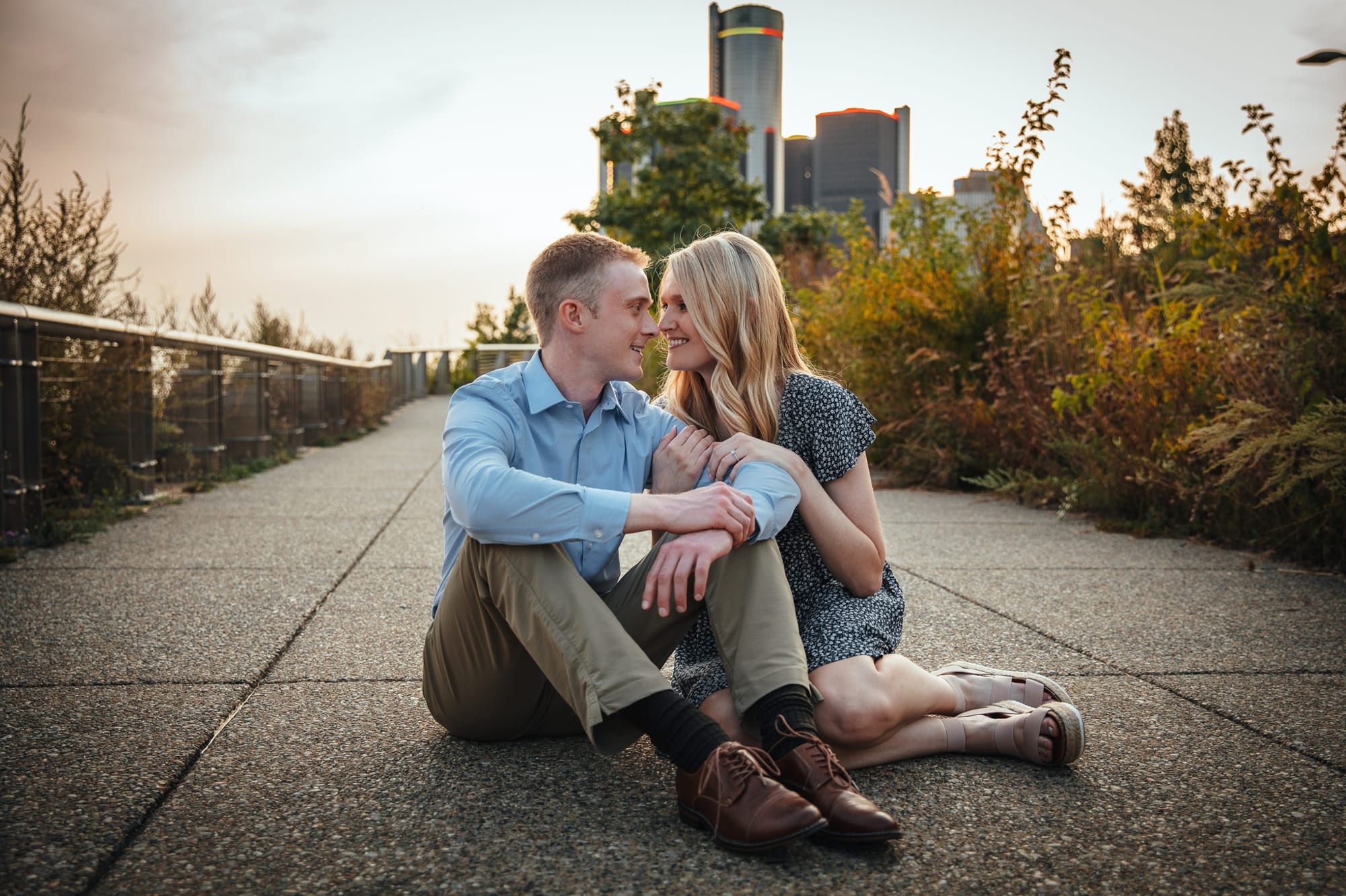 couple sitting on the sidewalk by Detroit riverfront