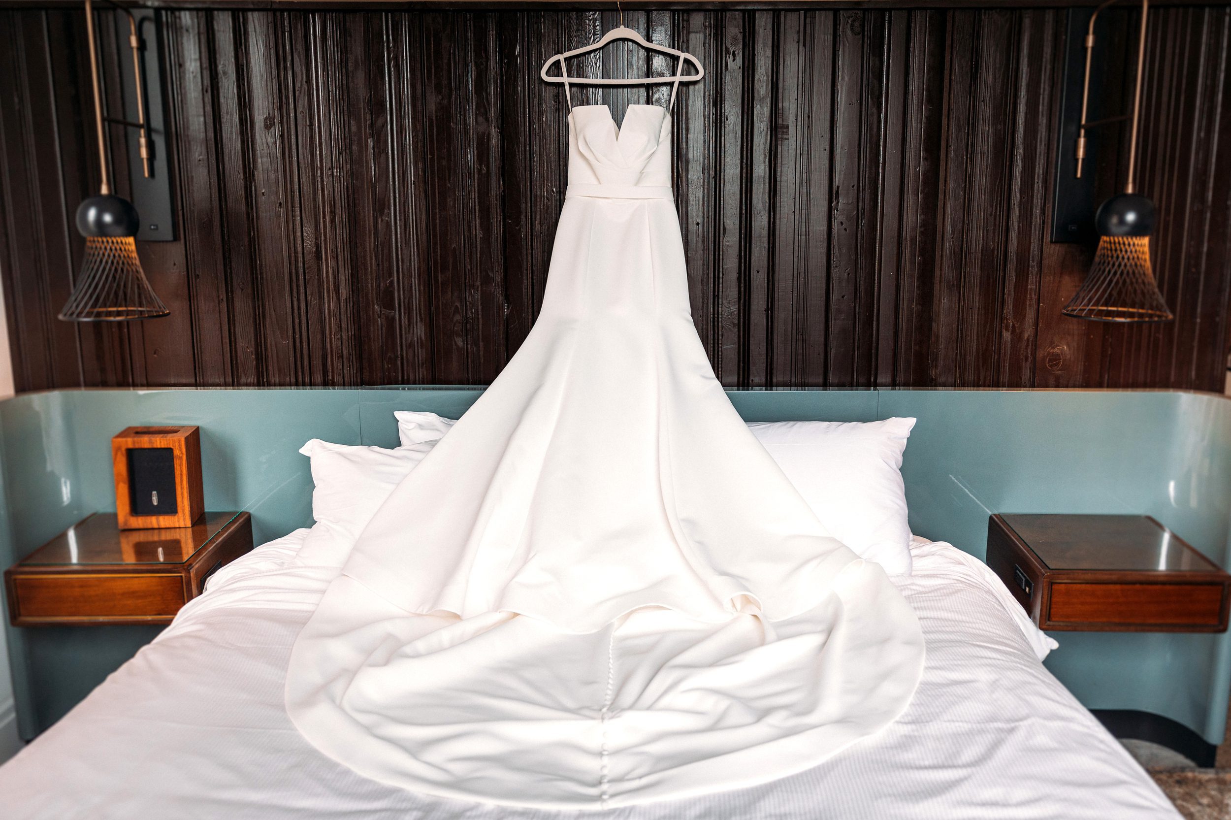 Wedding dress hanging above bed.