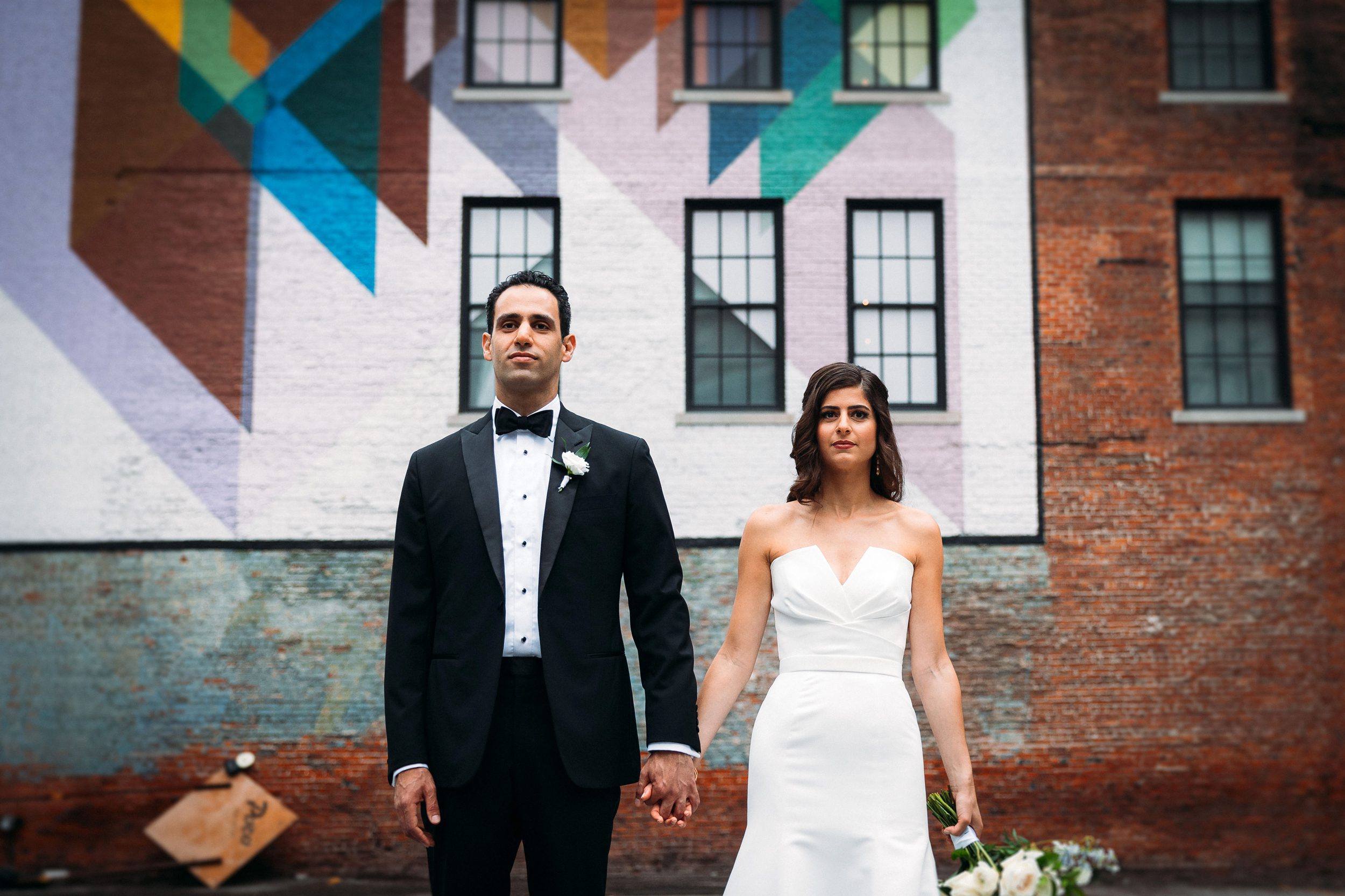 bride and groom in front of colorful mural
