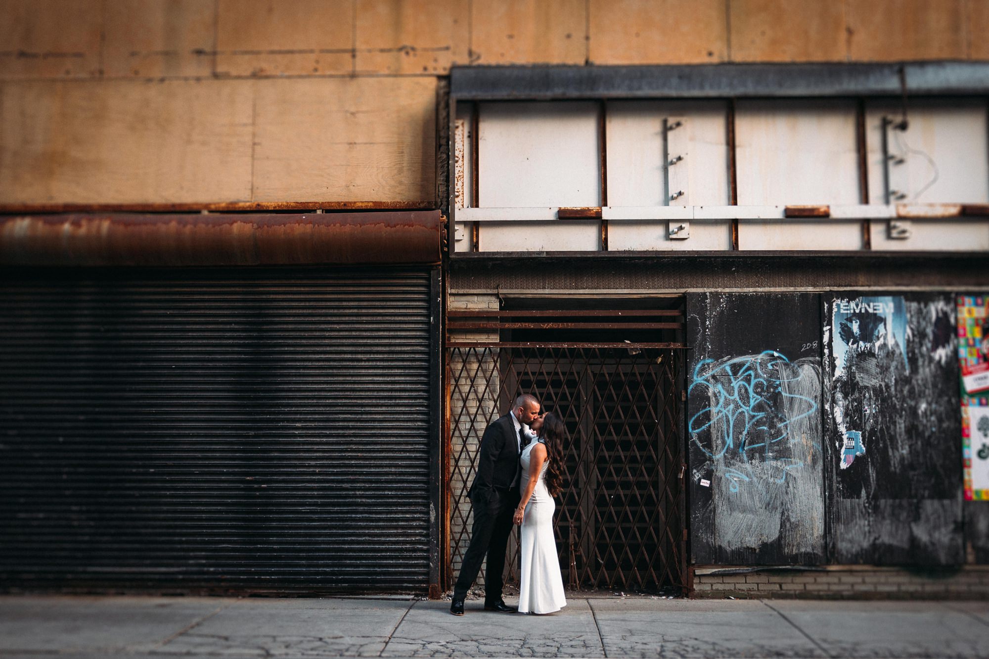 couple kissing in front of rundown building