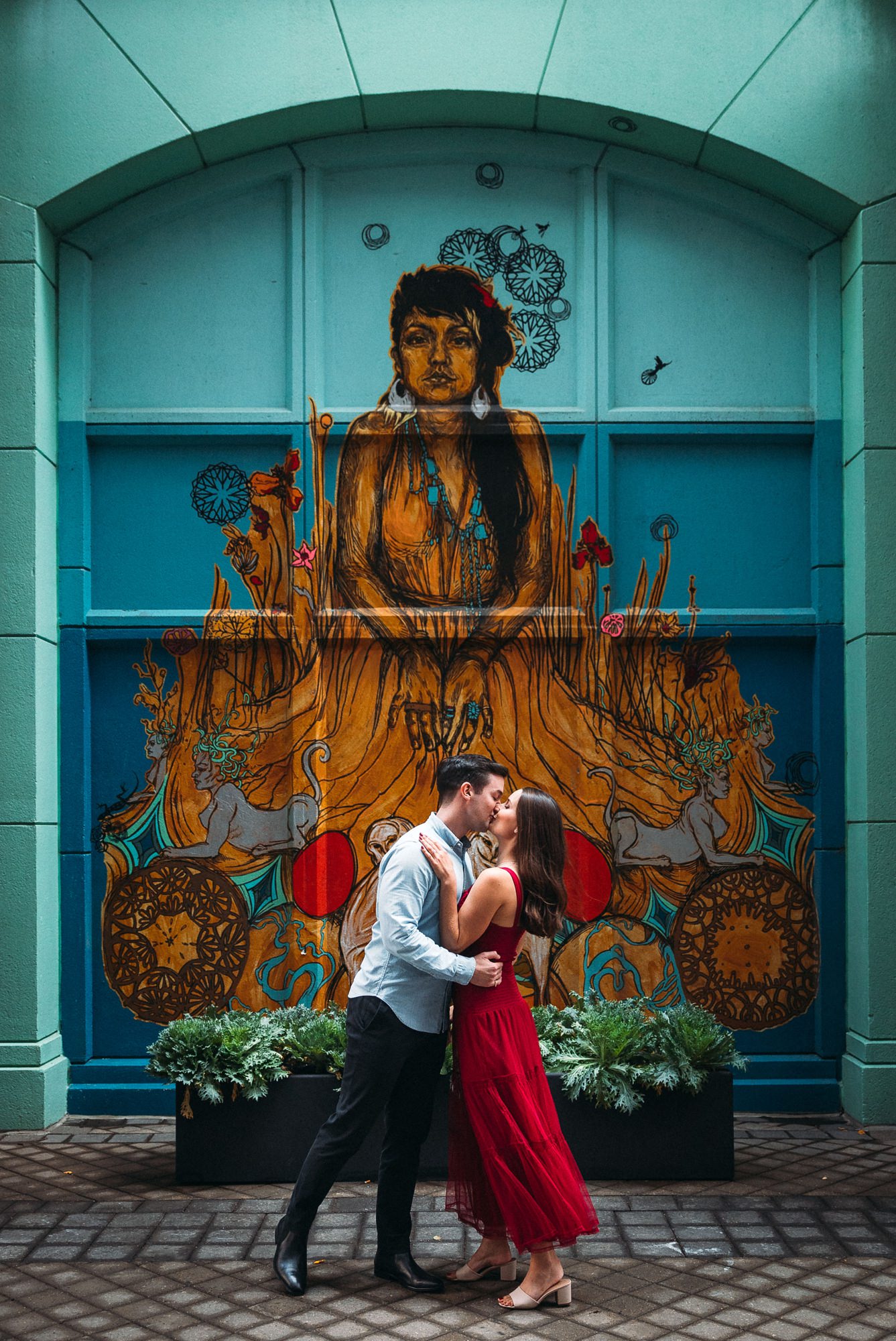 Couple kissing in front of mural
