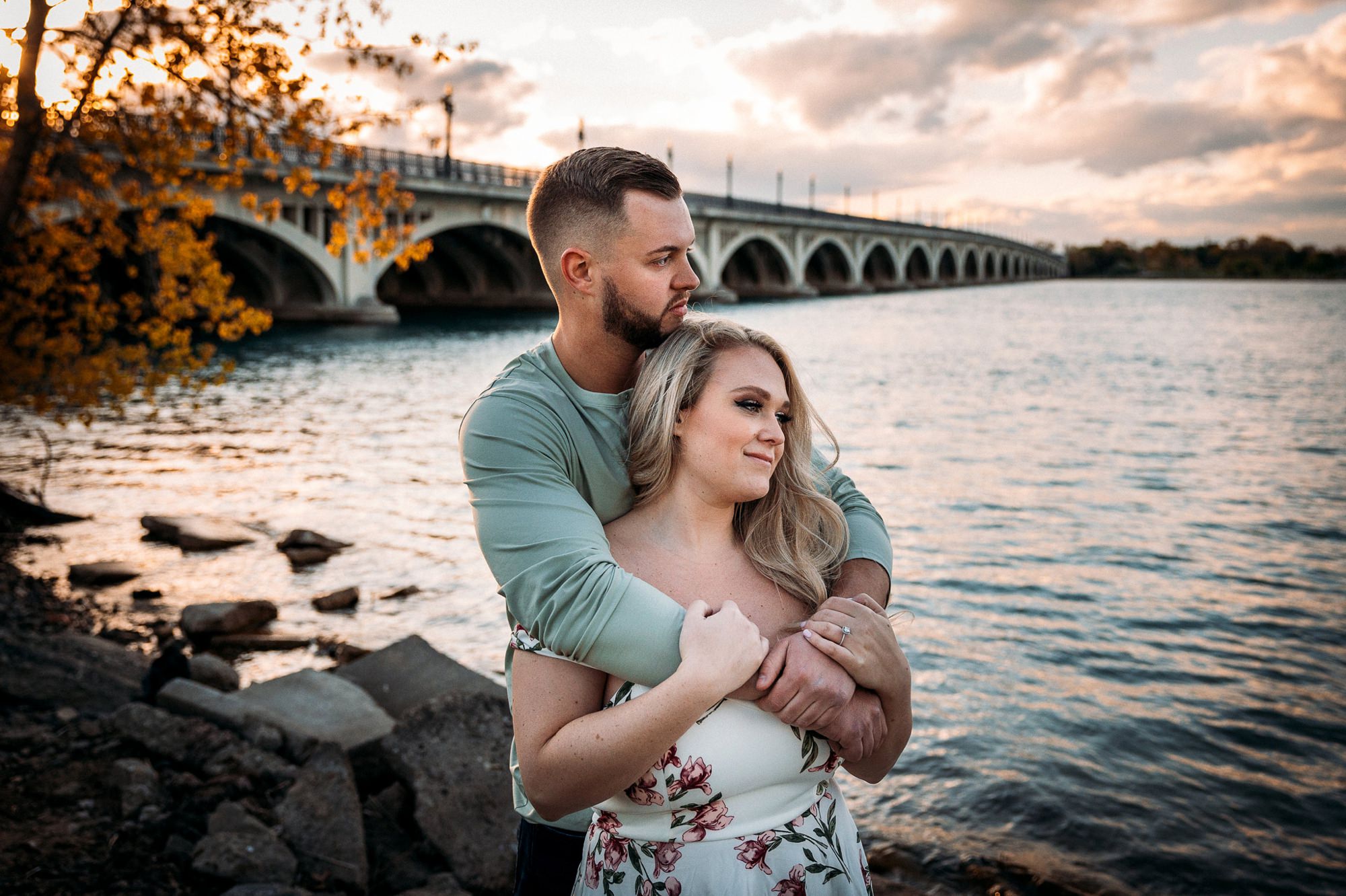 Couple hugging by a bridge at sunset