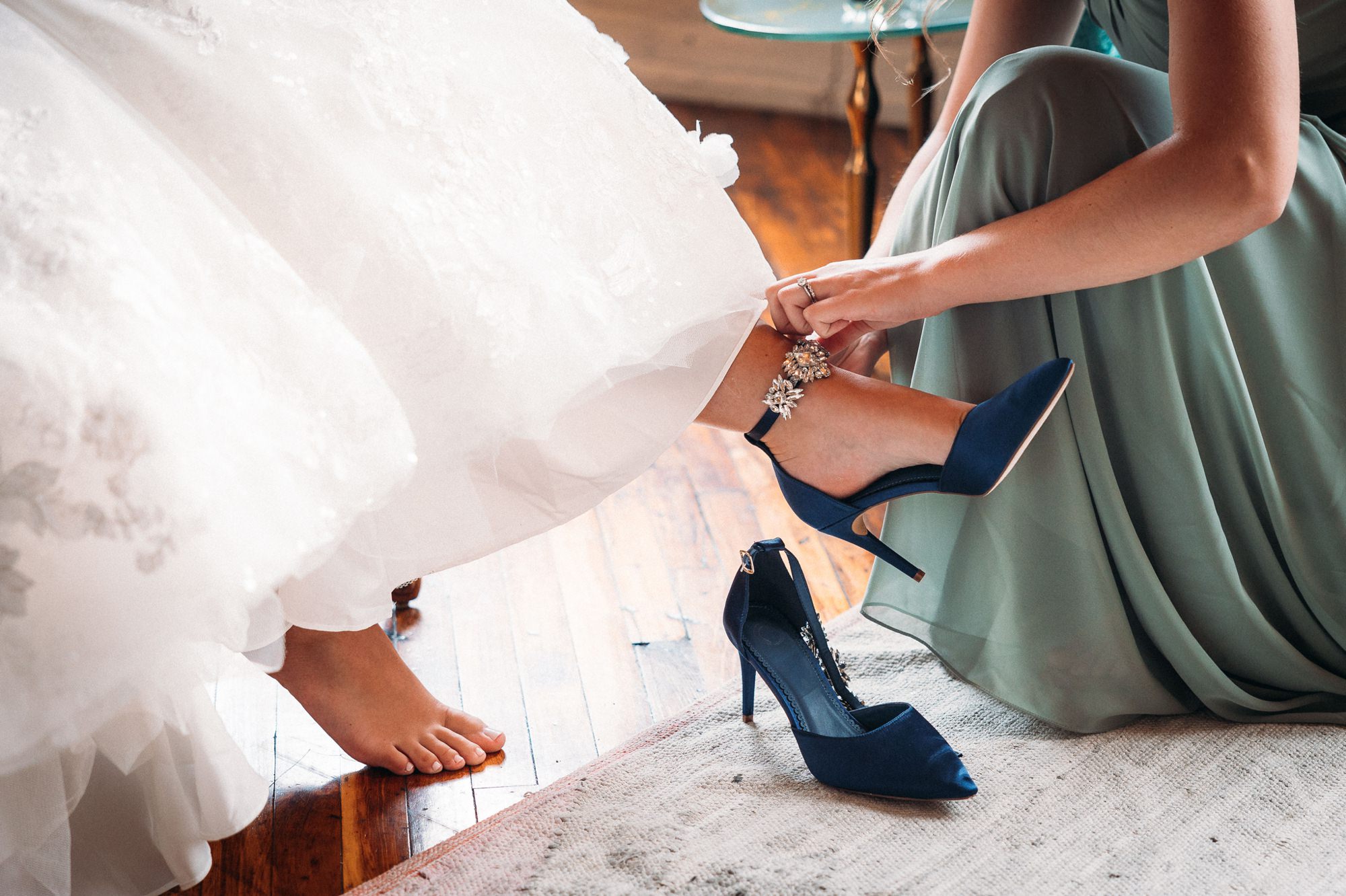 woman helping put on bride's shoe