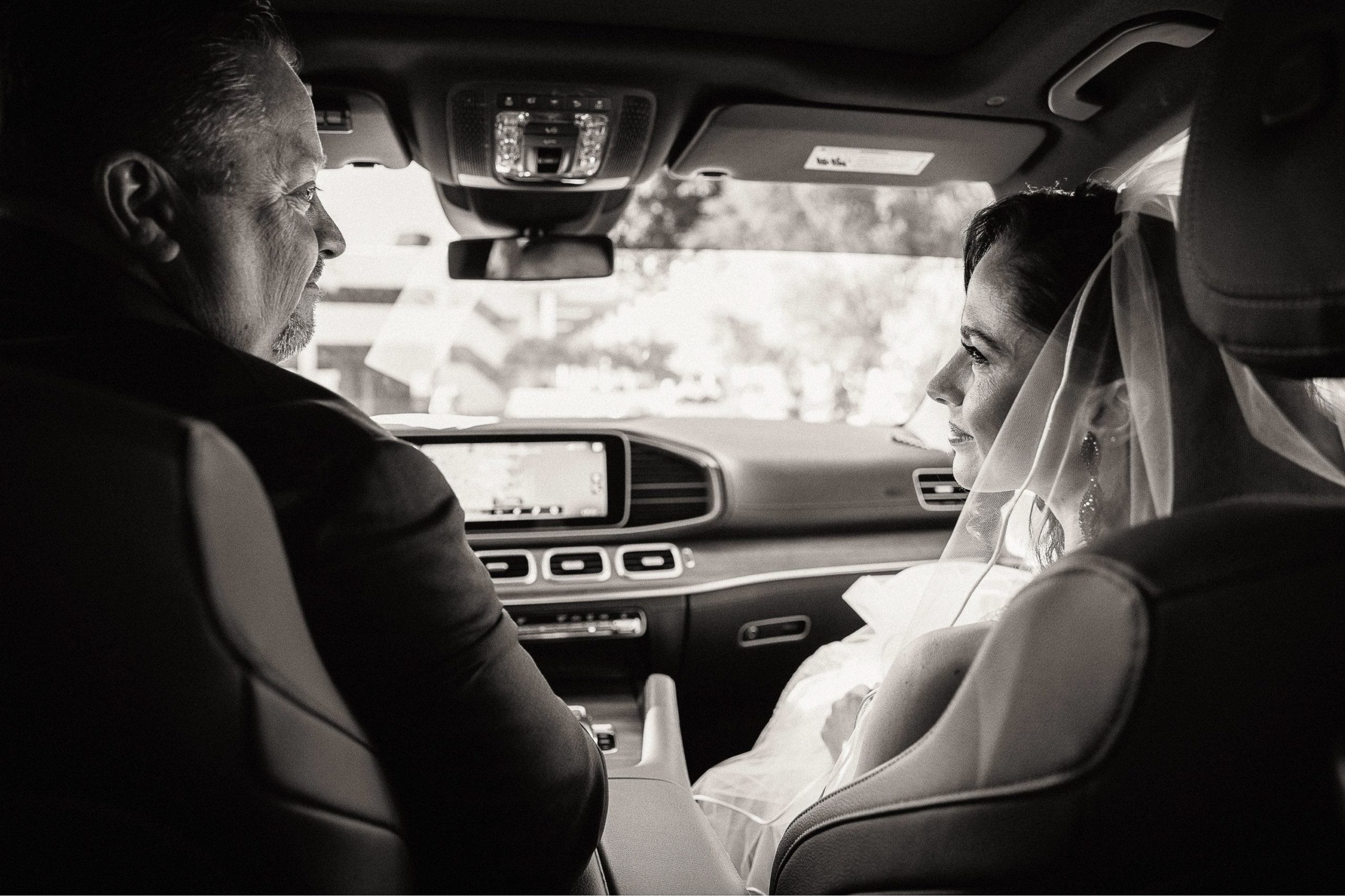 father and bride in front seat of car