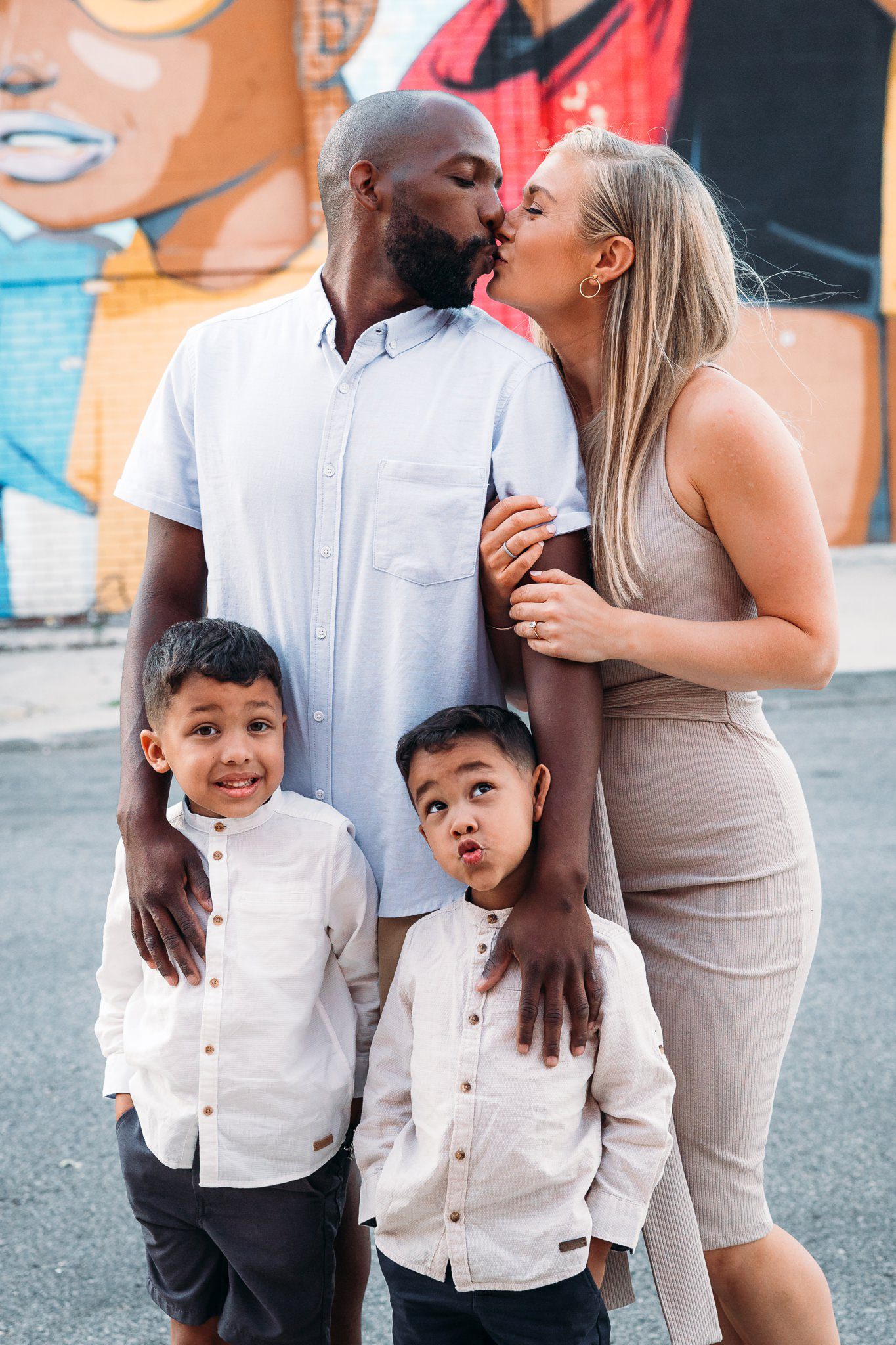 man and woman kissing, two kids making silly faces