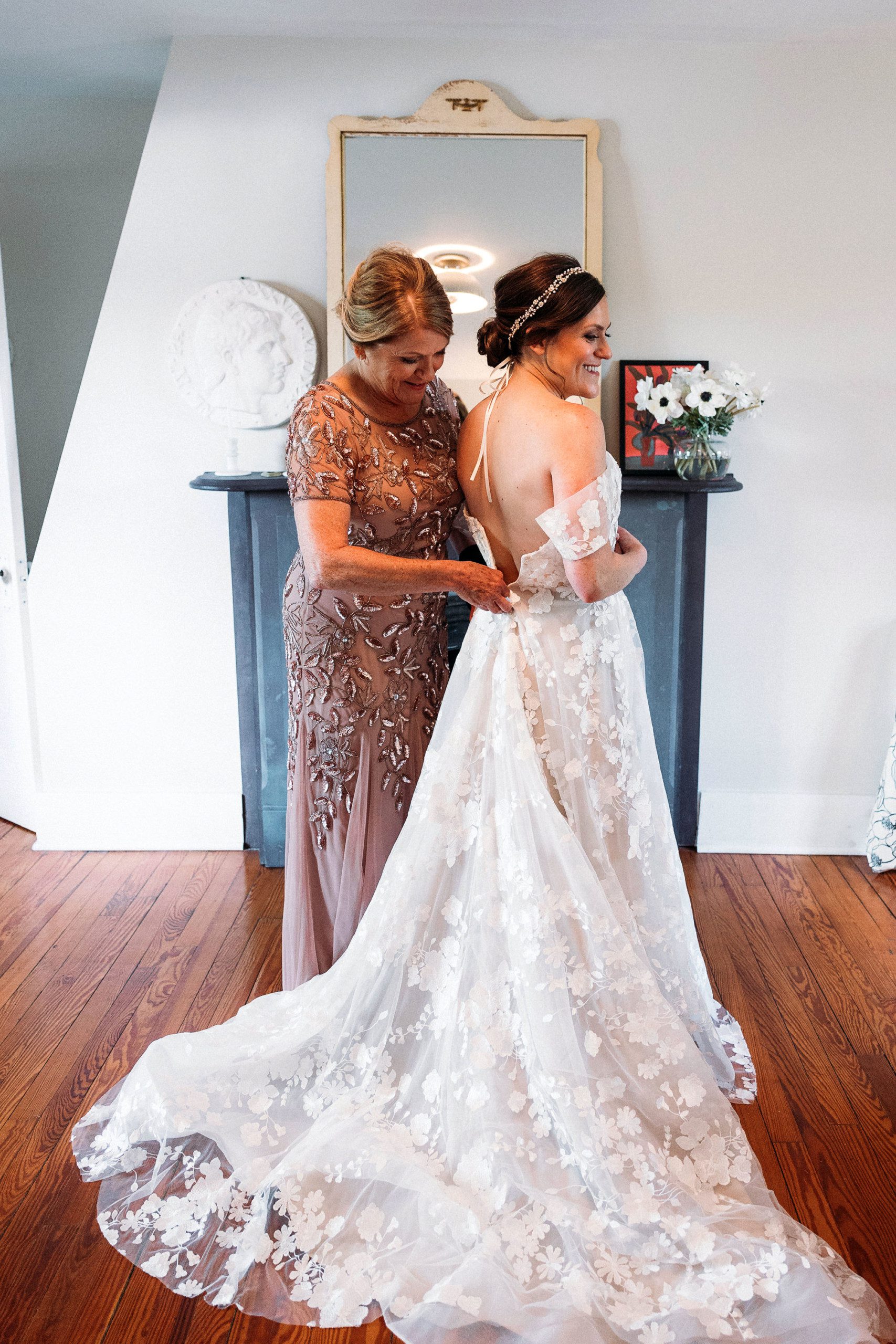 mother helping daughter with wedding dress
