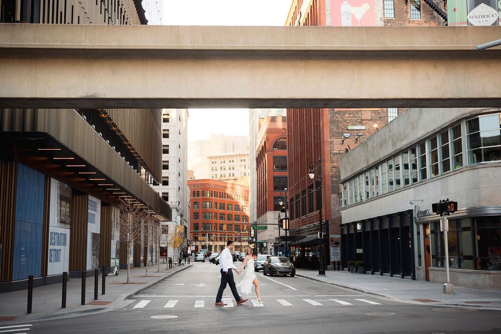 Couple in Semi Formal Wear, Holding Hands Crossing Street in Downtown Detroit for Engagement Photos